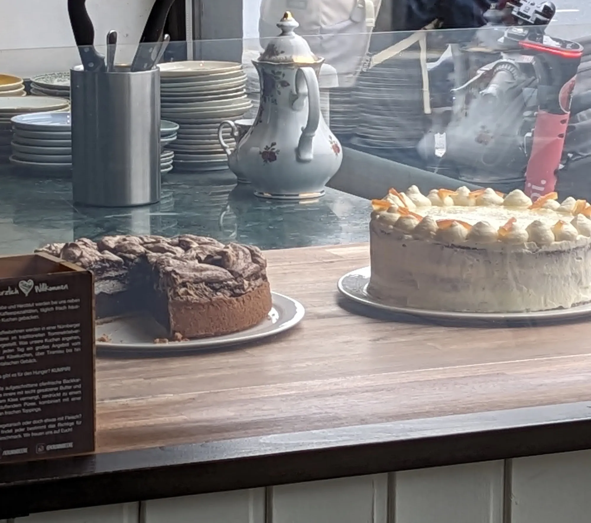 Hausgemachter Karottenkuchen und Schokoladenkuchen auf der Theke, dahinter eine Porzellankanne
