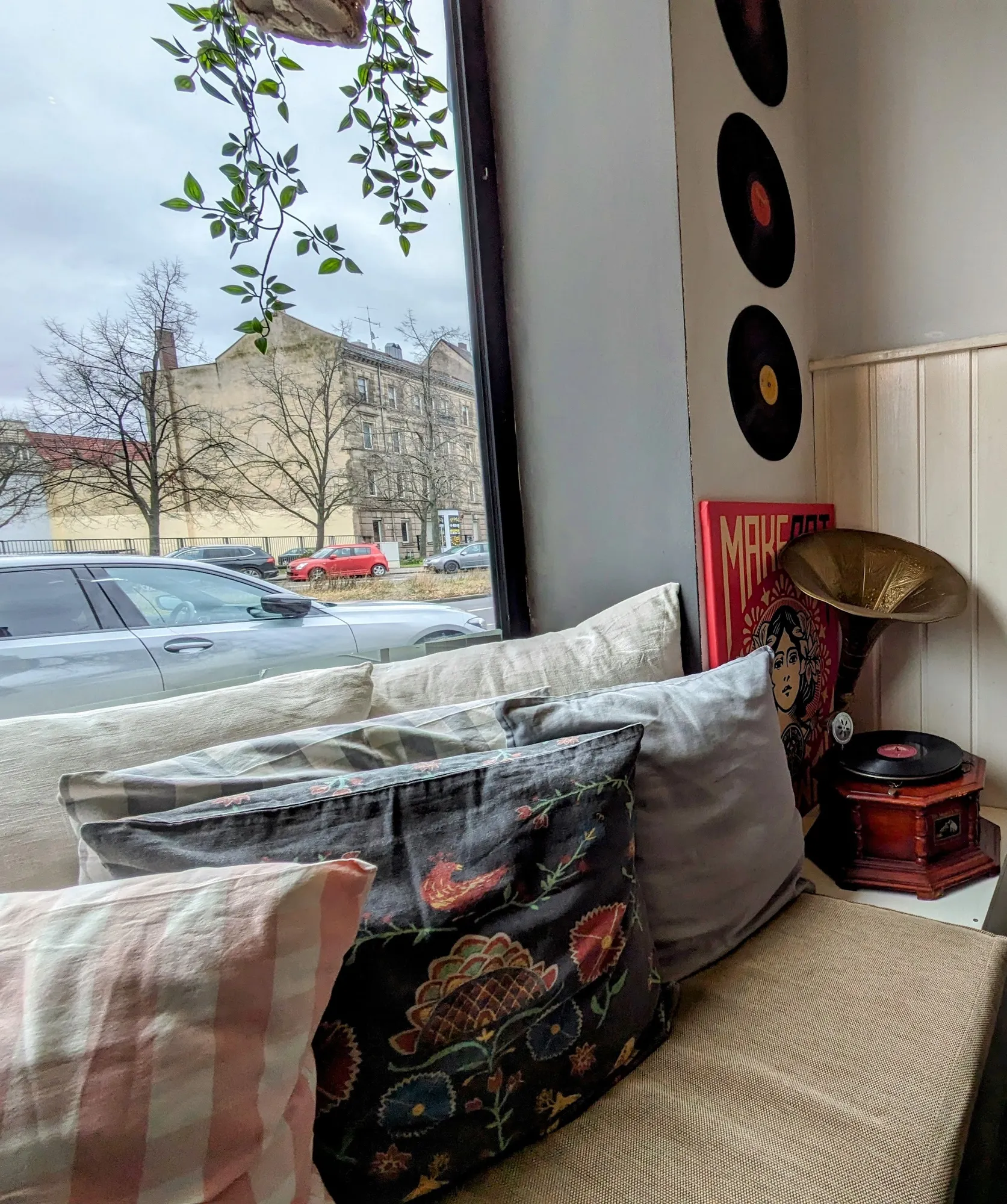 Gemütliche Fensterbank mit bestickten Kissen, Schallplatten an der Wand und einem Grammophon