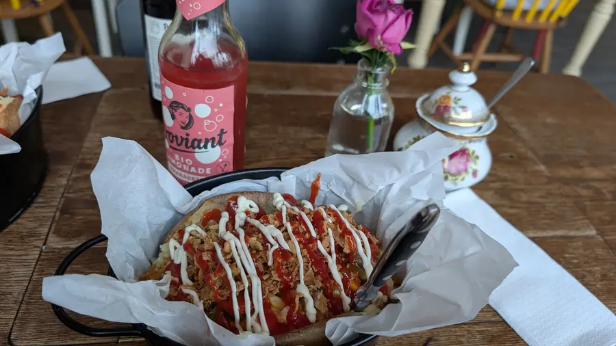 Kumpir mit Soße und Mayo, daneben Limonade und eine Rose in der Vase