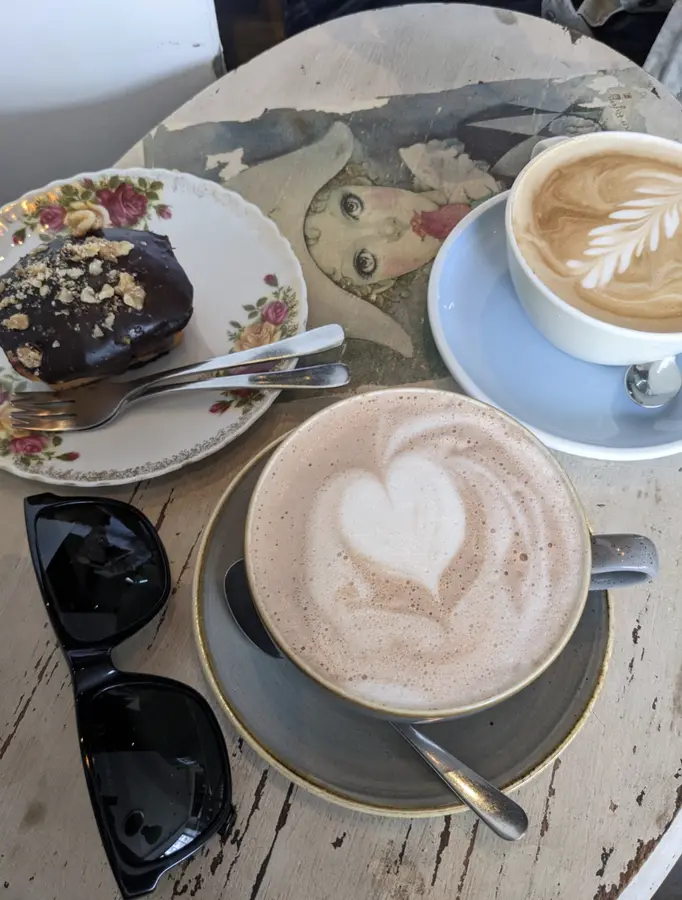 Cappuccino und Milchkaffee neben einem Schokoladenkuchen auf Rosenporzellan